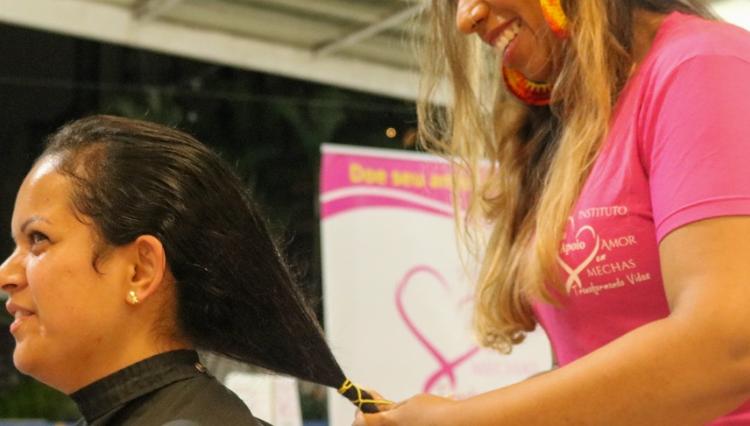 Cabeleireira voluntária corta cabelo de mulher no espaço cultural. 