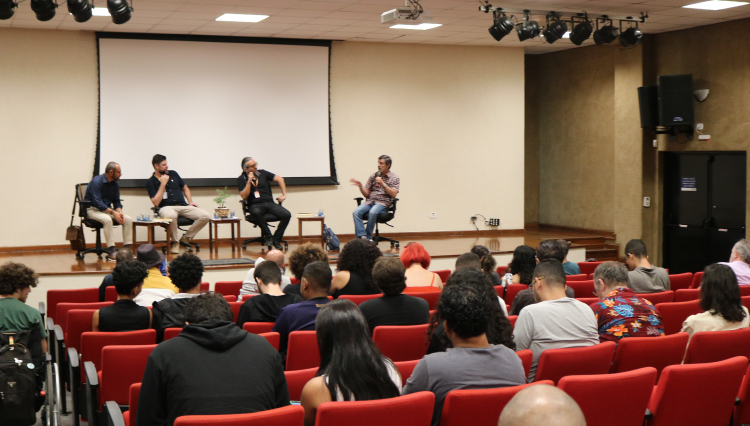 Professores, no palco, discutem os livros lançados na noite do aulão.