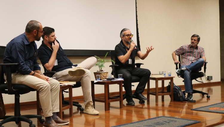 Professores, no palco, discutem os livros lançados na noite do aulão.