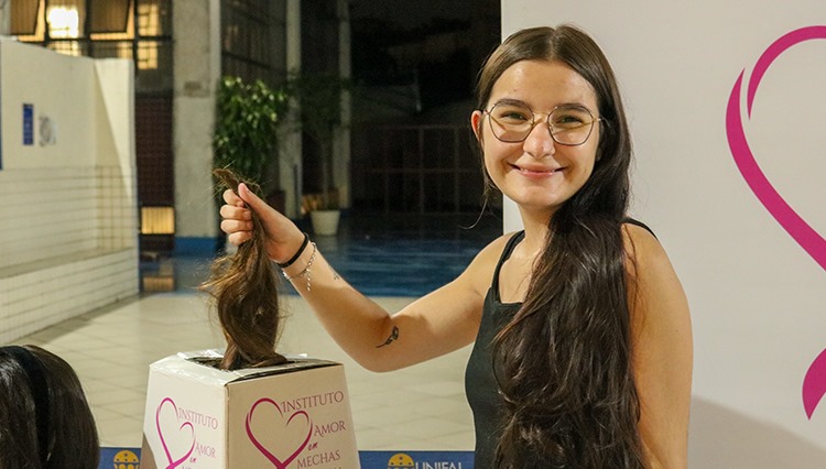 Doadora mostra para câmera a mecha de cabelo doada.