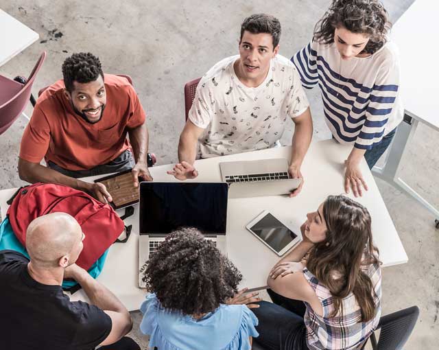 Grupo de pessoas reunidos ao redor de uma mesa em uma sala de reuniões.