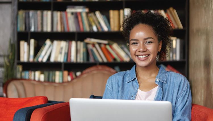 Jovem negra sorrindo enquanto usa um laptop