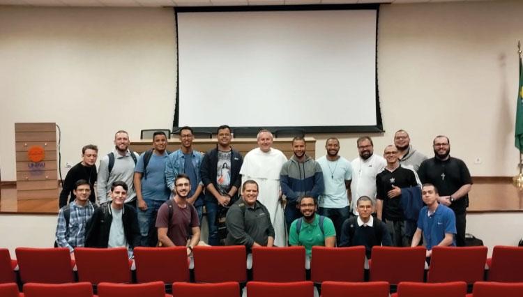 Alunos e Frei Philip-Neri Reese posando para foto no auditório do UNIFAI