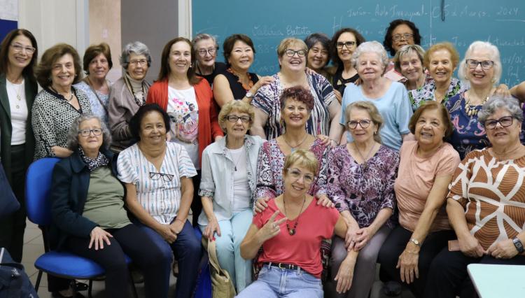 Grupo de 50 senhoras formandas juntas, posando para a foto, comemorando a formação no curso Universidade Aberta à Maturidade.