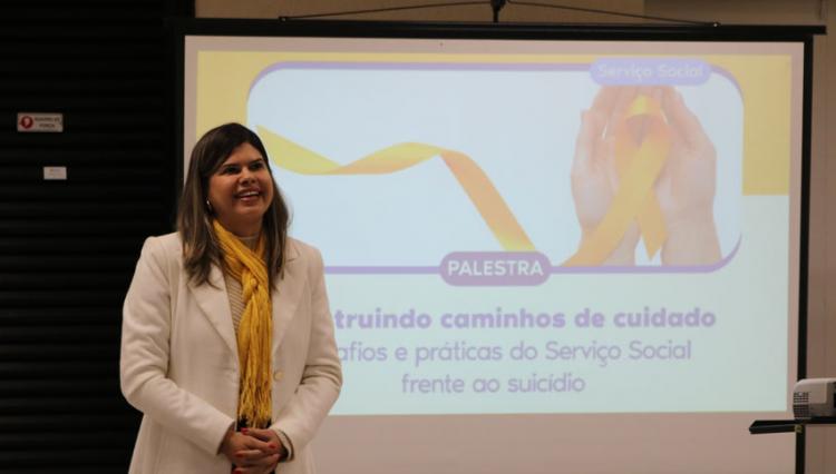 Palestrante em frente a projeção com o tema da palestra